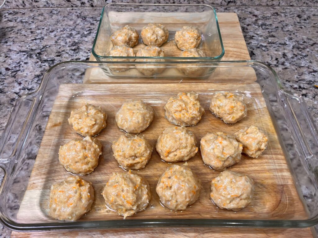 A baking sheet with Romanian meatballs arranged and ready to go into the oven for cooking