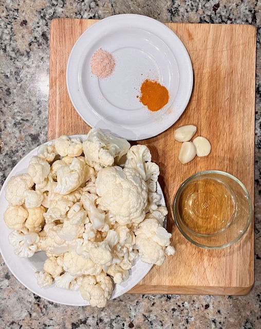 Ingredients for roasted cauliflower with garlic, turmeric, and spices, including cauliflower, garlic, turmeric, and other vegetables.