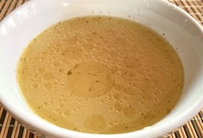 A bowl of AIP chicken bone broth with vegetables, a nutritious, collagen-rich drink for gut health and inflammation relief