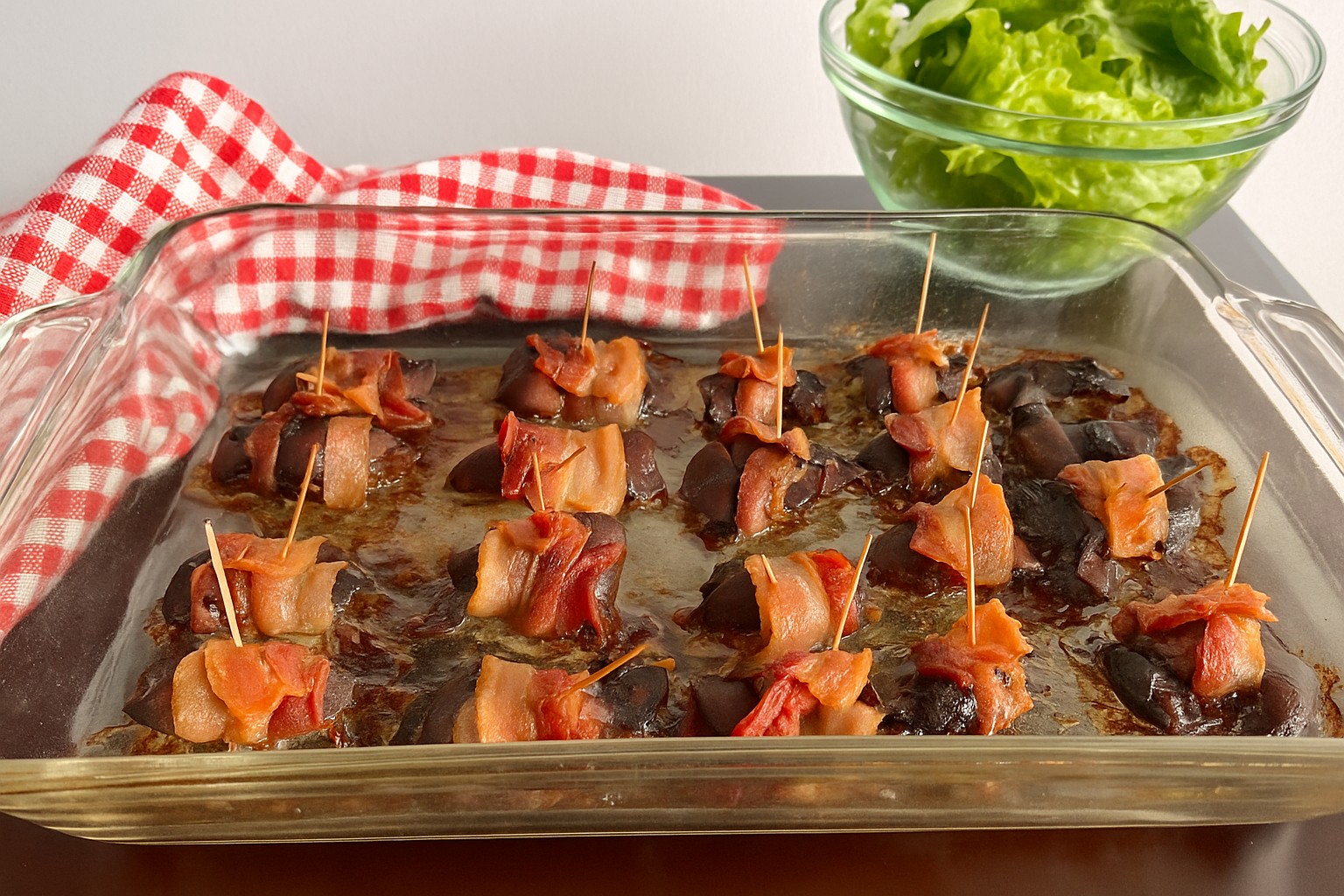 Bacon-wrapped chicken liver bites served with nutrient-dense kale, carrot ribbons, and purple cabbage salad on a wooden surface, AIP-friendly.