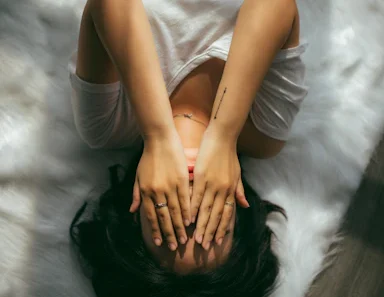 Chronic Stress and Autoimmune – person lying down with hands over face, symbolizing the overwhelming impact of chronic stress on autoimmune health.