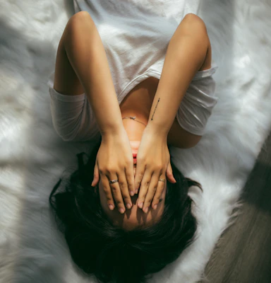 Chronic Stress and Autoimmune – person lying down with hands over face, symbolizing the overwhelming impact of chronic stress on autoimmune health.