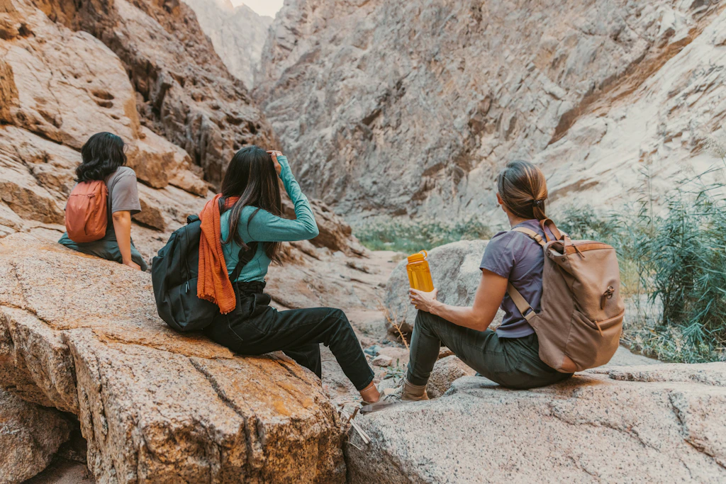 Group of people resting on stones on a mountain, reflecting on their AIP journey lifestyle, including exercise for wellness.