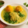 Creamy No-Tomato Chicken Dinner with mashed sweet potatoes and wilted greens, served in turmeric coconut sauce on a white plate with rustic props. Dairy-free, gluten-free, egg-free meal, perfect for those following an autoimmune diet.