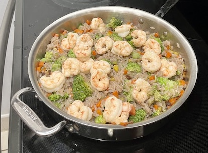 Cooked shrimp added to a skillet with cassava orzo, carrots, celery, and broccoli, completing the AIP-friendly Garlic Shrimp Cassava Orzo dish