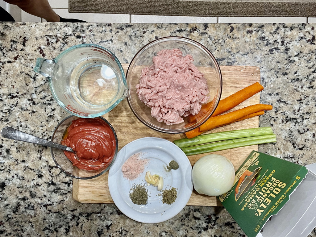 Ingredients for AIP-friendly Pasta Bolognese with green banana fusilli, including ground turkey, vegetables, no-tomato sauce, and green banana pasta.