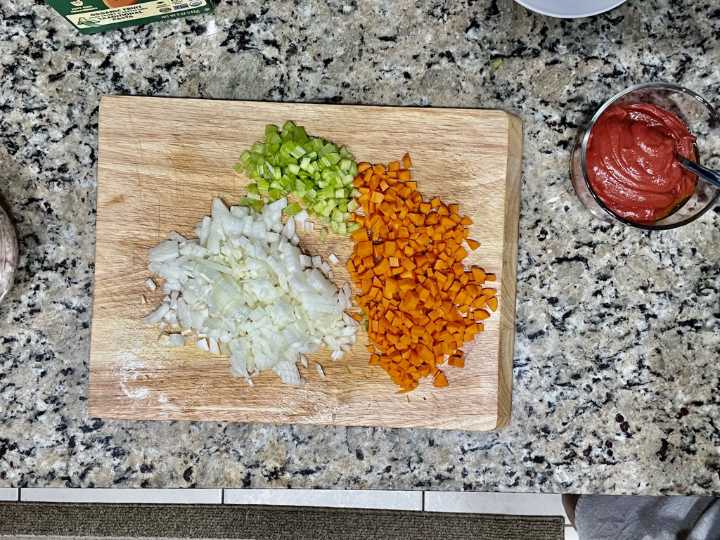 Diced vegetables including carrots, celery, and zucchini on a wooden cutting board for AIP-friendly, gluten-free, nightshades-free Turkey Pasta Bolognese.