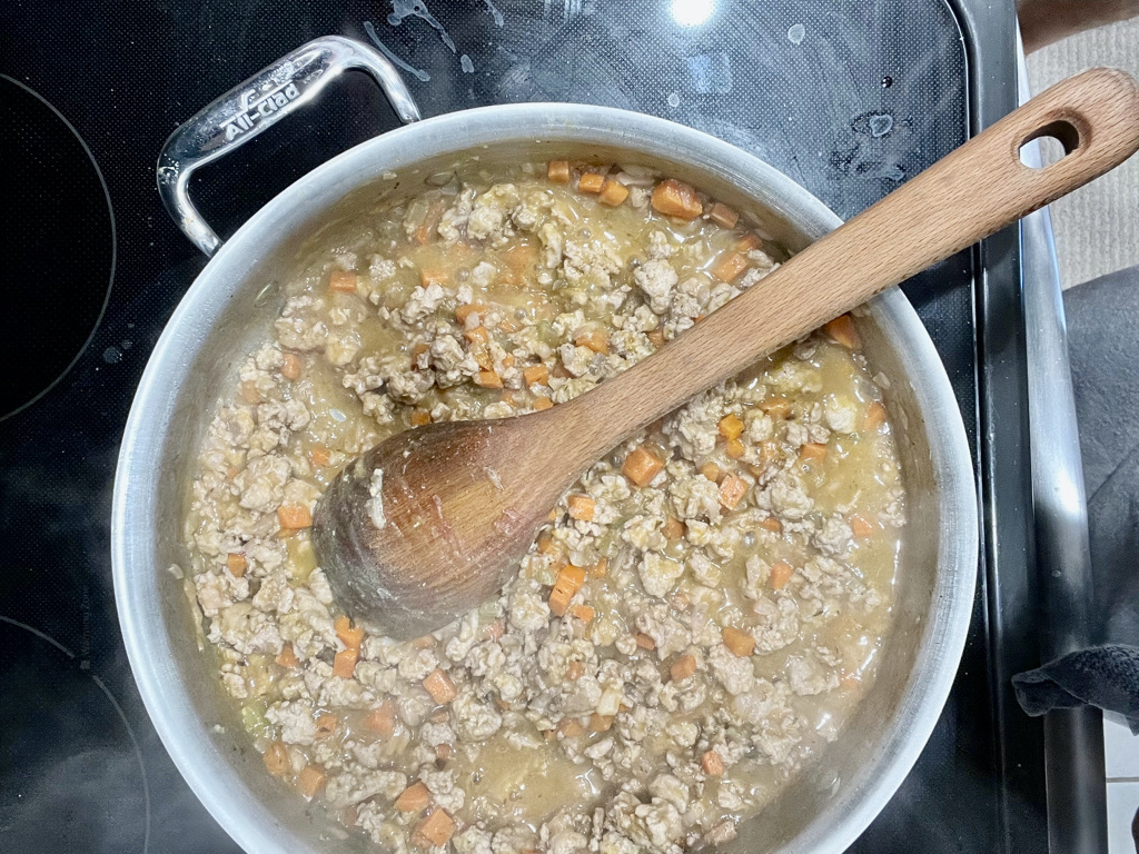 Pan on the stove with sautéed vegetables and ground turkey cooking for AIP-friendly Turkey Past Bolognese, gluten-free, nightshades-free.