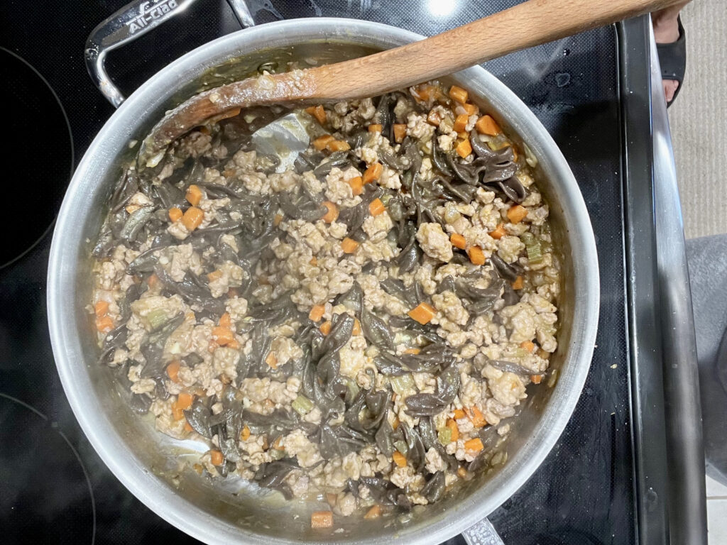 Pan on the stove with sautéed vegetables, ground turkey, and kale cooking for AIP-friendly Turkey Pasta Bolognese.