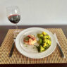 Bacon-wrapped pork chops with roasted garlic turmeric broccoli served on a plate.