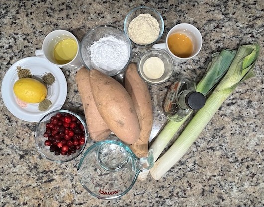 A selection of fresh ingredients for AIP-friendly sweet potato cups, including sweet potatoes, leeks, cranberries, coconut flour, avocado oil, and gelatin eggs. Gluten-free, nightshades-free, egg-free, dairy-free.