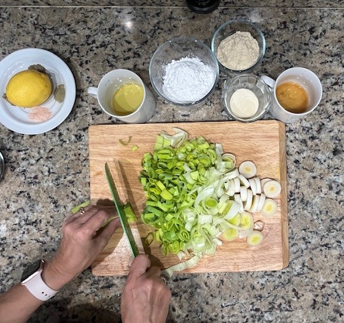 Slicing fresh leeks to prepare for the filling of AIP-friendly sweet potato cups, a key ingredient for a flavorful and healthy, gluten-free and egg-free appetizer.