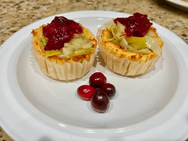 A beautifully plated serving of AIP-friendly sweet potato cups, filled with tender leeks and topped with vibrant cranberry sauce, showcasing a delicious, gluten-free, nutrition-dense and full of antioxidants appetizer. 