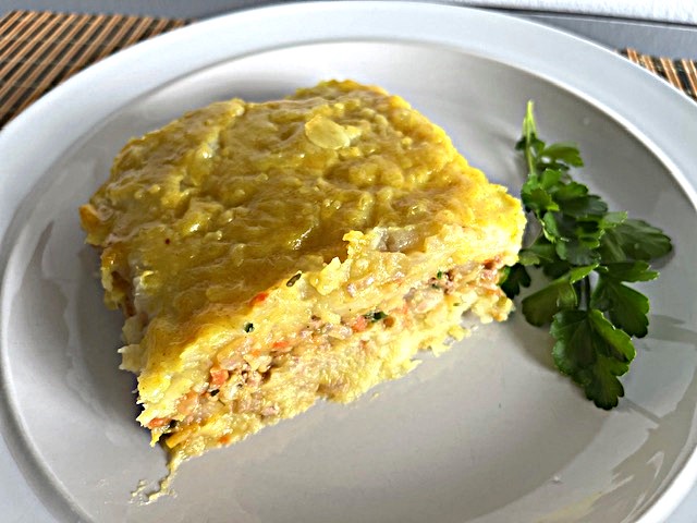 A plated serving of Turkey, Mashed Sweet Potato Moussaka, garnished with fresh herbs, on a white ceramic plate.