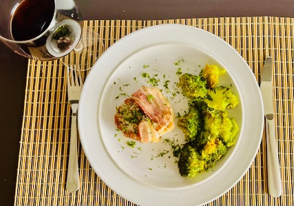 A plate of bacon-wrapped pork chops served with roasted garlic turmeric broccoli, ready to enjoy.