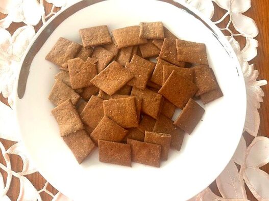 Homemade AIP crackers made with green banana flour, golden and crispy, arranged on a wooden plate, perfect for snacking or pairing with dips.