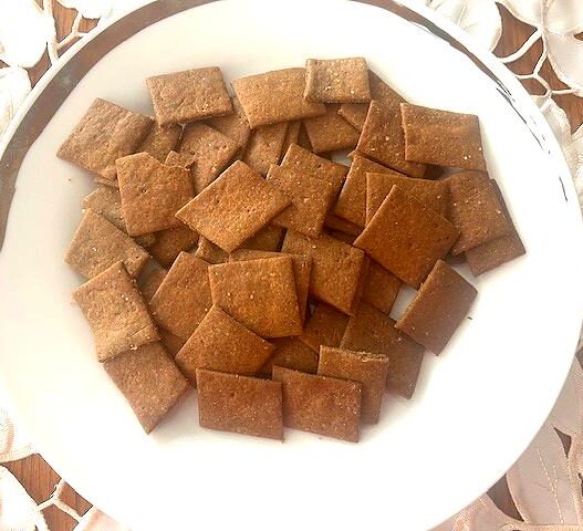 Homemade AIP crackers made with green banana flour, golden and crispy, arranged on a wooden plate, perfect for snacking or pairing with dips.