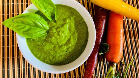 Garlic Kale Parmesan Pesto in a bowl, garnished with fresh basil leaves. Perfect for those in the AIP reintroduction phase, supporting gut health.