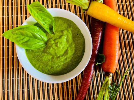 Garlic Kale Parmesan Pesto in a bowl, garnished with fresh basil leaves. Perfect for those in the AIP reintroduction phase, supporting gut health.