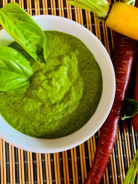 Garlic Kale Parmesan Pesto in a bowl, garnished with fresh basil leaves. Perfect for those in the AIP reintroduction phase, supporting gut health.