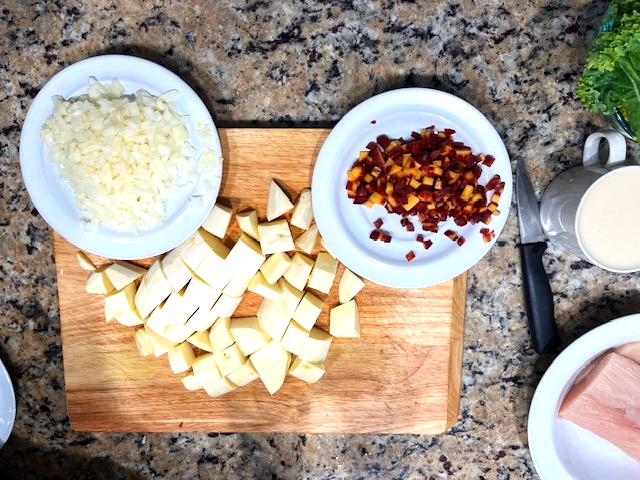 Chopping ingredients for Cardamom-Infused Mahi-Mahi Curry, including zucchini, carrot, sweet potato, kale, and fresh mahi-mahi.