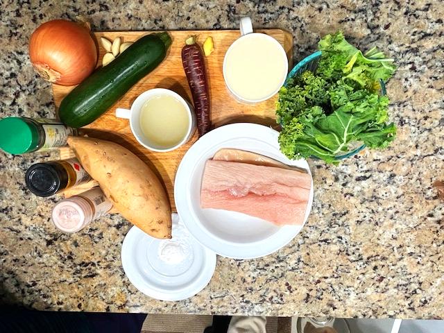 Ingredients for Cardamom-Infused Mahi-Mahi Curry including mahi-mahi, zucchini, carrot, sweet potato, kale, coconut milk, and spices.