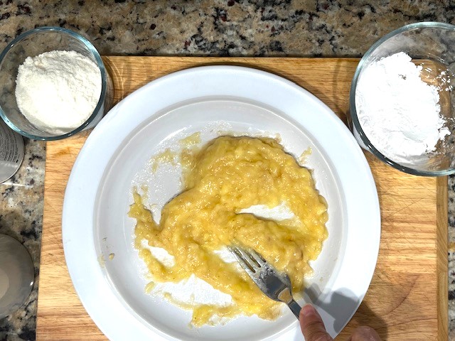 Mashed banana on a plate, ready to make Delicious AIP Banana Pancakes, gluten-free, dairy-free, and AIP-compliant.