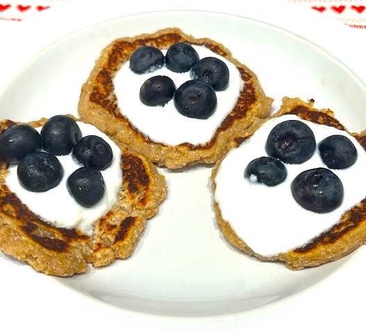 Three Delicious AIP Banana Pancakes topped with coconut yogurt and fresh blueberries on a white plate. A perfect gluten-free, dairy-free, and healthy breakfast!