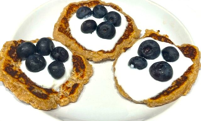 Three Delicious AIP Banana Pancakes topped with coconut yogurt and fresh blueberries on a white plate. A perfect gluten-free, dairy-free, and healthy breakfast!