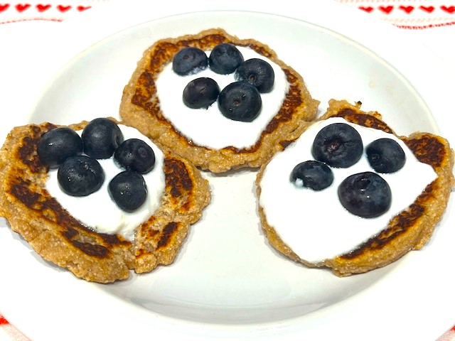 Three Delicious AIP Banana Pancakes topped with coconut yogurt and fresh blueberries on a white plate. A perfect gluten-free, dairy-free, and healthy breakfast!