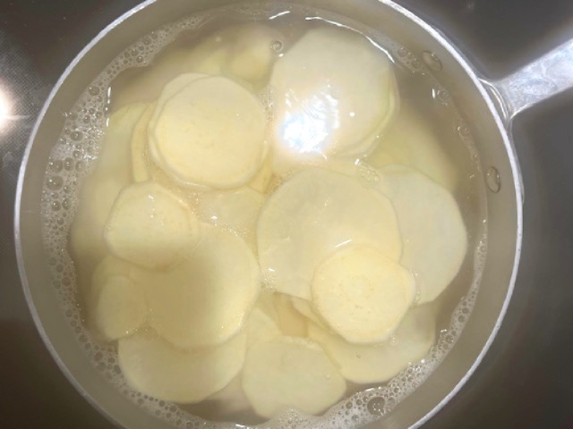 Parboiling sweet potatoes in a pot for an AIP Reintroduction Garlic Shrimp and Sweet Potato Gratin, a gluten-free, nightshade-free recipe perfect for autoimmune-friendly diets.