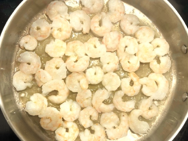 Shrimp cooking in a skillet with avocado oil, prepared for an AIP Reintroduction Garlic Shrimp and Sweet Potato Gratin, a gluten-free, nightshade-free dish.