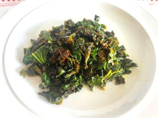 Kale Sautéed with Cumin and Ghee served on a white plate, garnished with lemon juice.