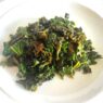 Kale Sautéed with Cumin and Ghee served on a white plate, garnished with lemon juice.