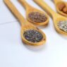 Nuts and seeds arranged on wooden spoons, including almonds, pumpkin seeds, and sunflower seeds.