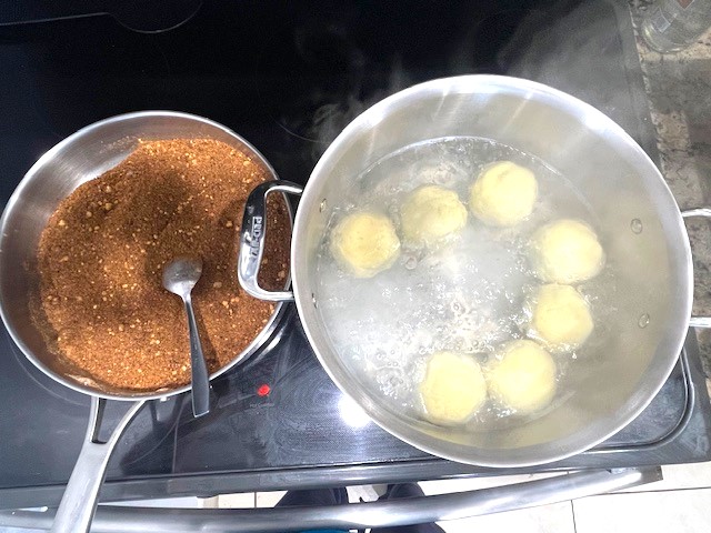 Removing AIP-Friendly Plum Dumplings from boiling water and rolling them in tigernut coating. A gluten, dairy, nut, and nightshade-free dessert, perfect for egg reintroduction on the Autoimmune Diet.