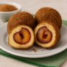 AIP-friendly plum dumplings on a white plate, sliced to reveal a juicy plum center, placed on a green cloth napkin with rustic props — gluten-free, dairy-free, egg-free, autoimmune paleo dessert.