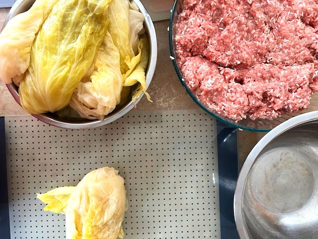 Preparing Romanian Cabbage Rolls (Sarmale), filling sauerkraut leaves with a pork and rice mixture.