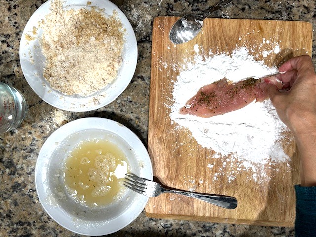 Coating a chicken breast with tapioca flour as the first step for the Tastiest Chicken Breast Schnitzel, a gluten-free, dairy-free, egg-free recipe.