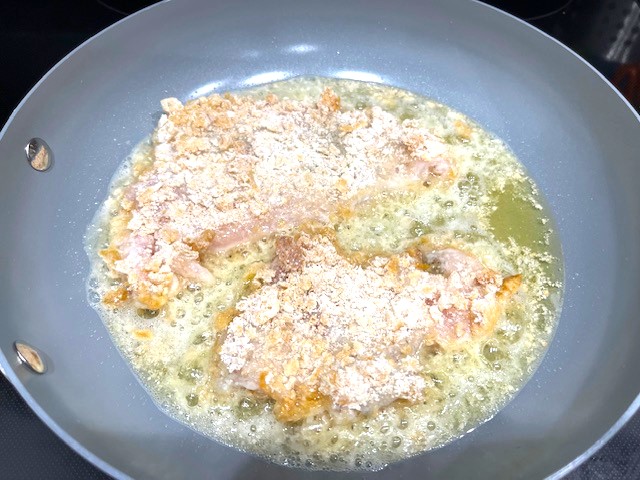 Cooking a coated chicken breast in a pan for the Tastiest Chicken Breast Schnitzel, a gluten-free, dairy-free, egg-free recipe.