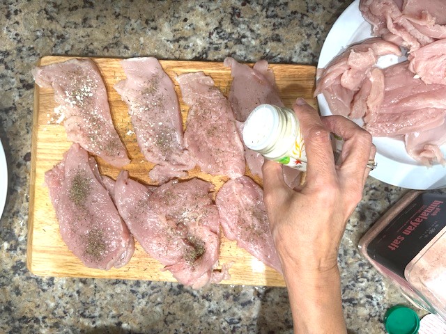 Seasoning butterflied chicken breasts with salt, garlic powder, and thyme for the Tastiest Chicken Breast Schnitzel, a gluten-free, dairy-free, egg-free recipe.