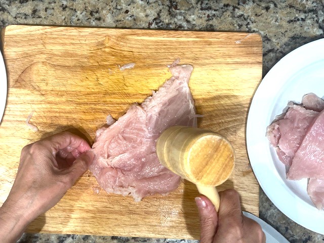 Tenderizing a butterflied chicken breast with a mallet for the Tastiest Chicken Breast Schnitzel, a gluten-free, dairy-free, egg-free recipe.