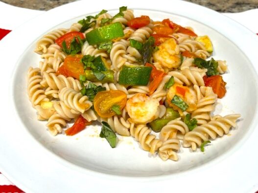 Shrimp and Veggie Pasta served on a white plate, featuring zucchini, asparagus, cherry tomatoes, and gluten-free pasta. An AIP Reintroduction, gluten-free, dairy-free meal packed with fresh vegetables.