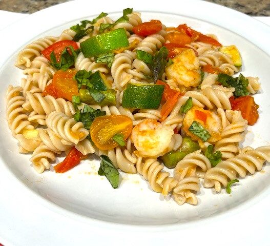 Shrimp and Veggie Pasta served on a white plate, featuring zucchini, asparagus, cherry tomatoes, and gluten-free pasta. An AIP Reintroduction, gluten-free, dairy-free meal packed with fresh vegetables.