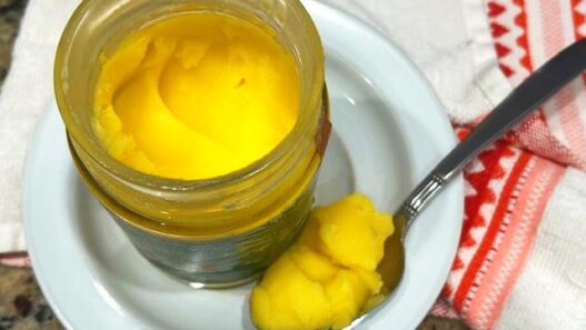 A jar of ghee on a wooden countertop, ideal for Recipes with Ghee in the AIP Reintroduction Phase