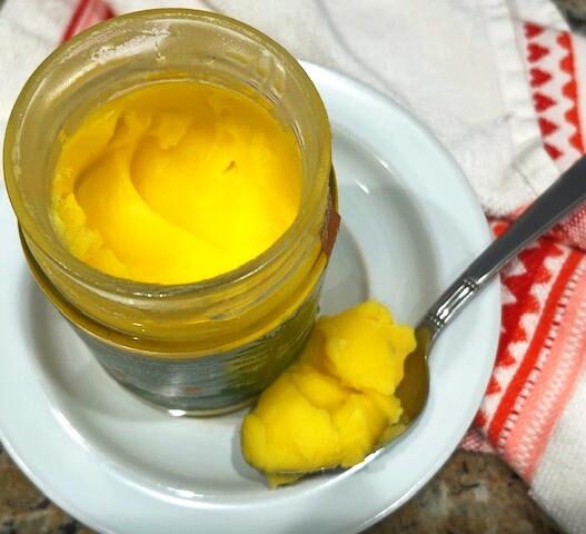 A jar of ghee on a wooden countertop, ideal for Recipes with Ghee in the AIP Reintroduction Phase