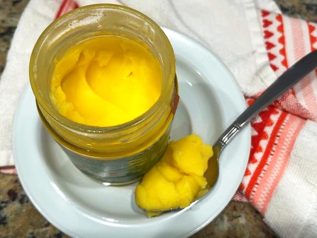 A jar of ghee on a wooden countertop, ideal for Recipes with Ghee in the AIP Reintroduction Phase