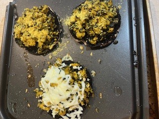 Stuffed portobello mushrooms on a baking sheet, topped with turkey-kale filling and optional dairy-free