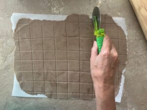 Crunchy Tasty AIP Crackers dough being cut into squares with a pizza cutter – cassava-free, gluten-free, paleo, autoimmune protocol friendly.