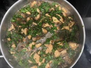 AIP Chicken Mongolian Style cooking in a pan with chicken, mushrooms, and fresh dandelion greens. Gut health recipe that is gluten free, dairy free, soy free, and nightshades free.